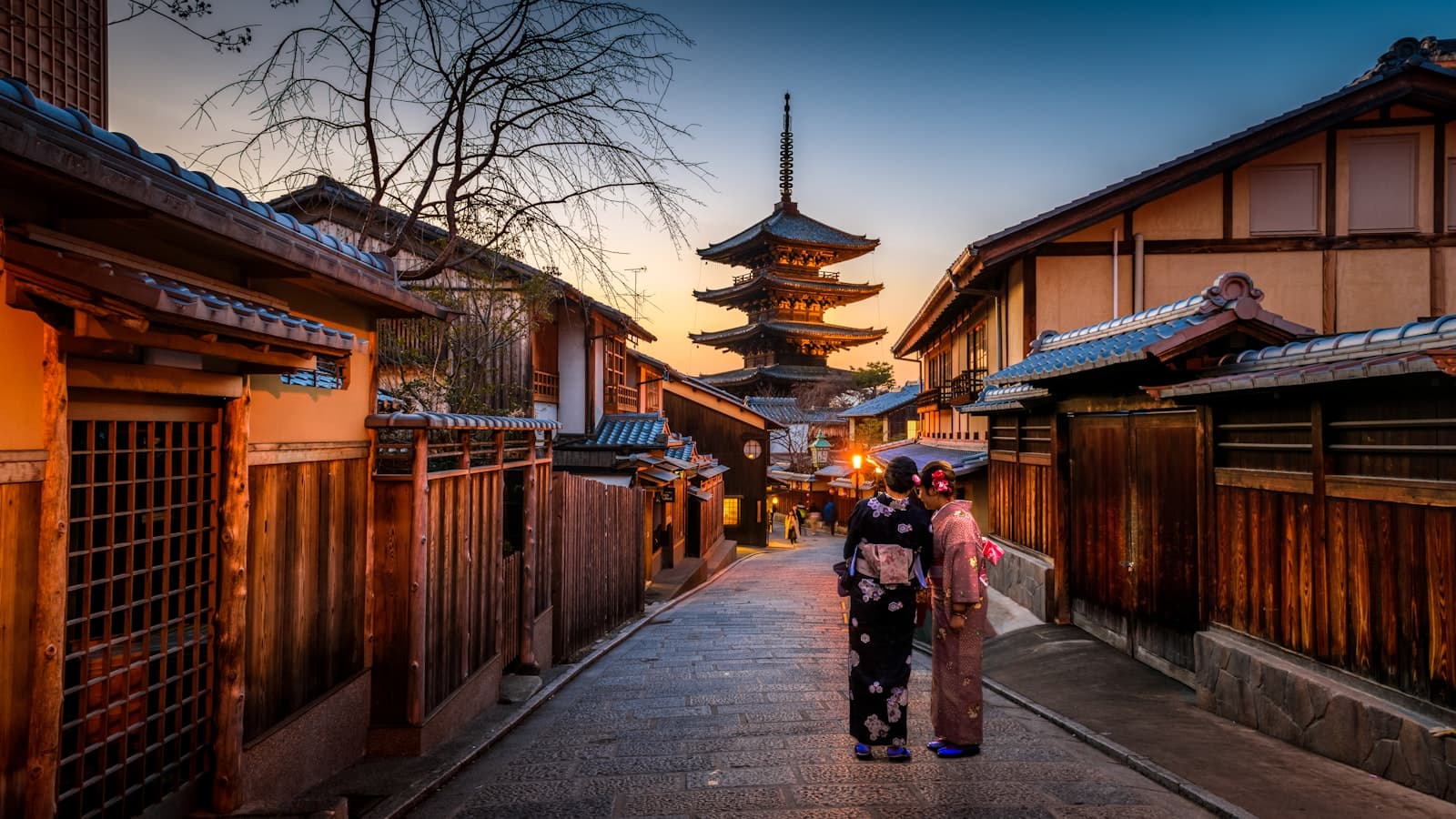 Kyoto street at dusk with a pagoda and two people in kimono
