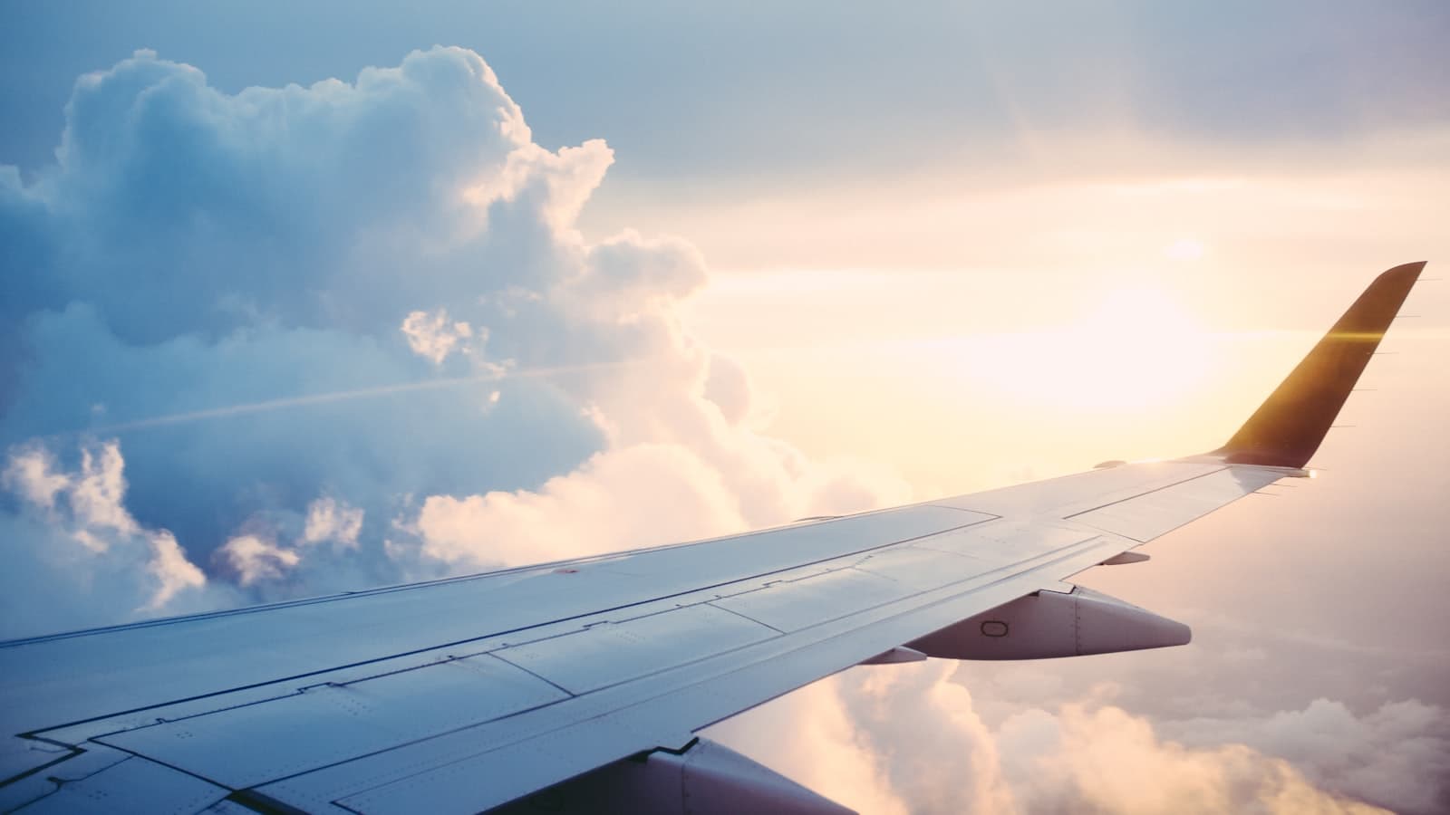 Airplane wing above clouds at sunset