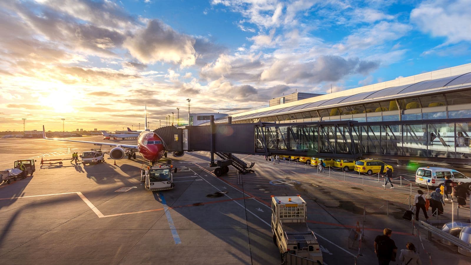Airport jet bridge and service vehicles at sunset