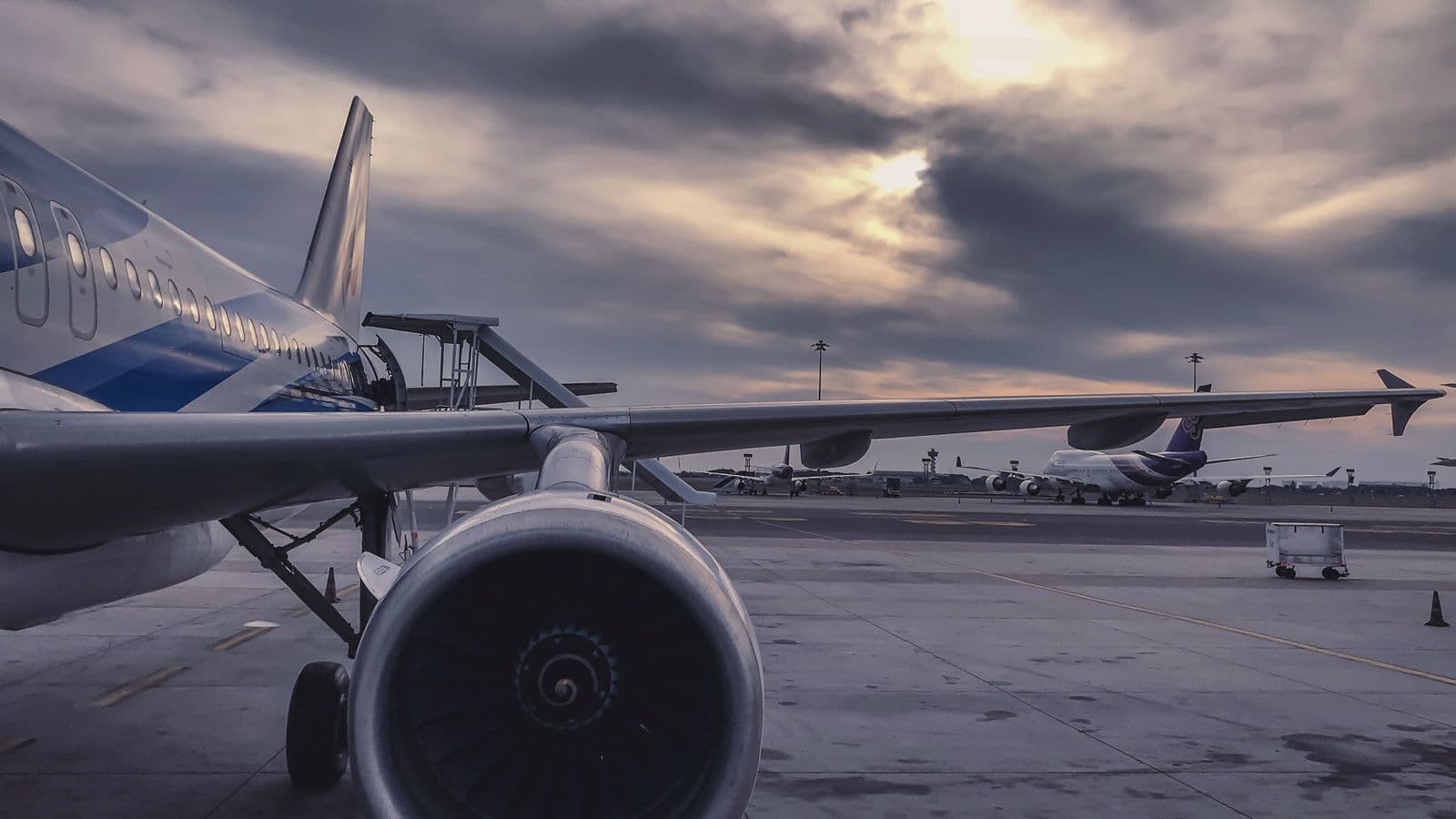 Jet engine on an airport tarmac under a cloudy sky